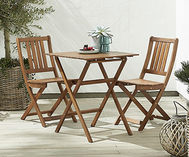Dve drvene baštenske stolice i sto u bašti 