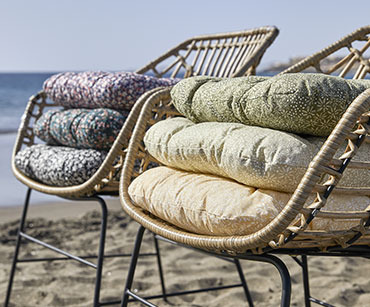 Cvetni baštenski jastuci na baštenskim stolicama na plaži