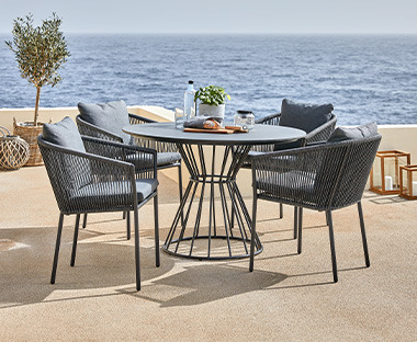 Crni okrugli baštenski sto i 4 stolice na terasi sa pogledom na more