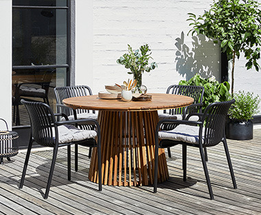 Drveni baštenski sto i crne stolice u bašti
