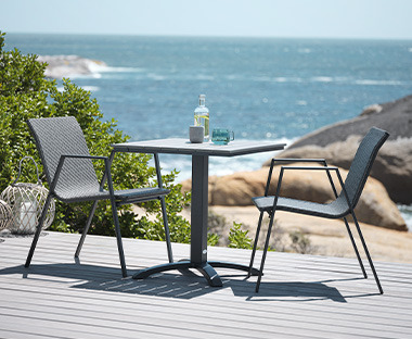 Crni bistro stočić i dve stolice na terasi sa pogledom na more