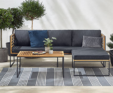 Lounge sofa natur boje sa tamno sivim jastucima u bašti