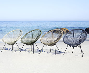 Metalne baštenske lounge stolice različitih boja na plaži