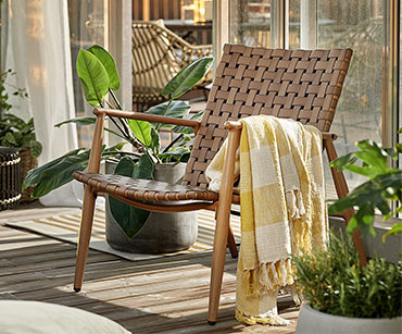 Lounge stolica natur boje sa žutim ćebetom na balkonu