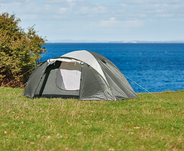 Sivi šator na travi pored vode