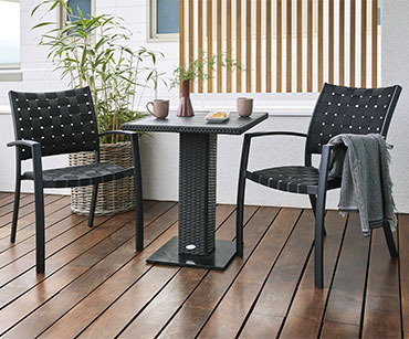 Bistro sto i dve crne baštenske stolice na terasi drvenih podova