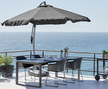 Suncobran iznad baštenskog seta sa 4 stolice na velikoj terasi sa pogledom na more