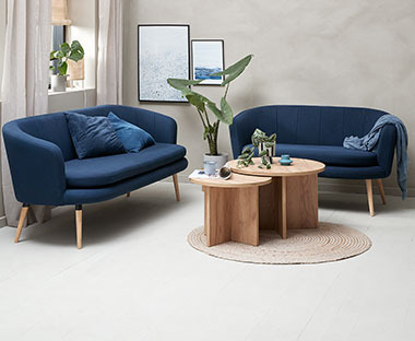 Dnevna soba sa dva plava kauča i drvenim okruglims točićima