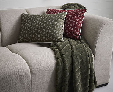 Novogodišnji jastučići zelene i bordo boje i tamno zeleno ćebe na bež kauču