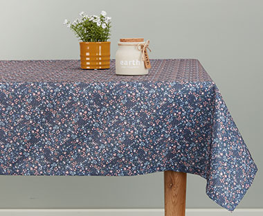 Plavi cvetni stolnjak na drvenom trpezarijskom stolu