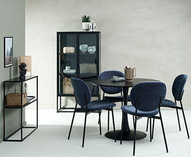 Trpezarija sa crnim, modernim nameštajem, okruglim stolom i tamno plavim stolicama