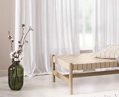Dnevni krevet, zelena vaza na podu i providne bele zavese