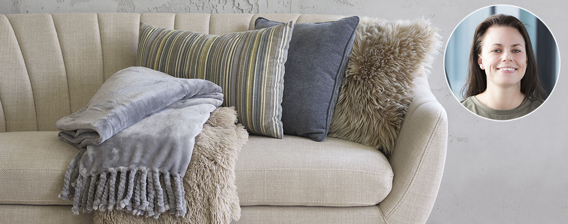 Sofa sa ćebetom, prugastim i plavim ukrasnim jastukom i jastukom od veštačkog krzna
