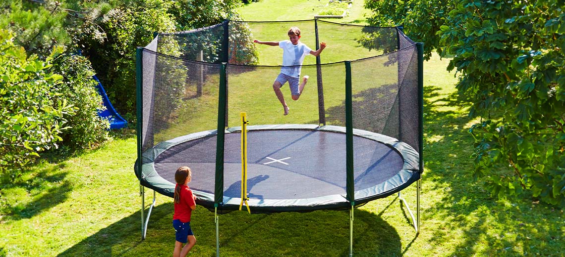 Deca se igraju na velikoj trambolini u bašti