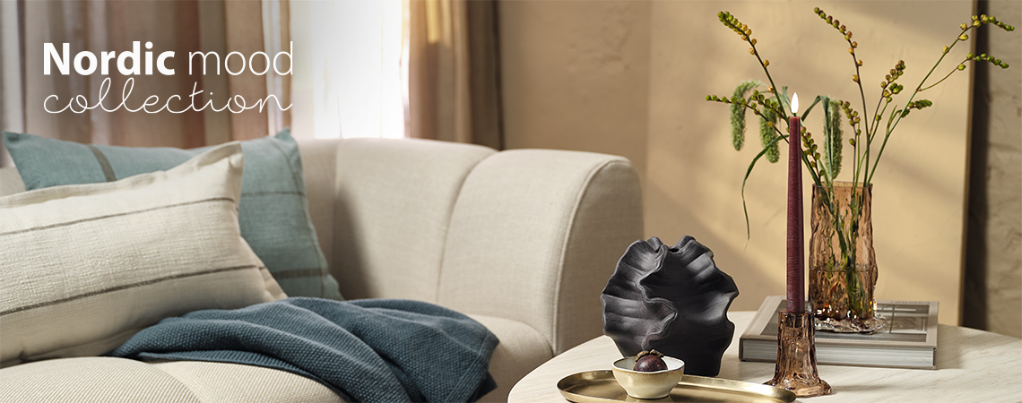 Dnevna soba sa sofom i stočićem sa staklenom vazom i svećnjakom