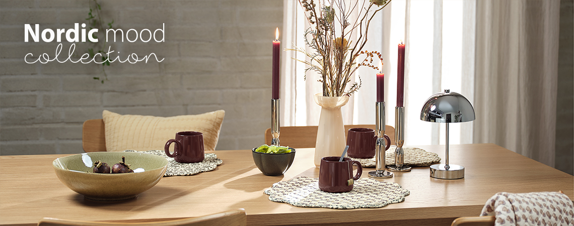 Velika SIGURD činija, MELVIN šolje, EJLIF činija, ENGSNELLE stoni podmetači, VISTI vaza sa FRANZ veštačkim buketom, ADRIAN svećnjaci i KENT lampa na baterije Trpezarijski sto sa činijama, šoljama, stonim podmetačima, vazom, svećnjacima i lampom na baterije