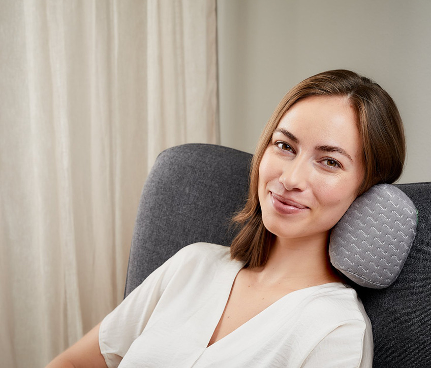Žena sedi u fotelji sa jastukom za vrat