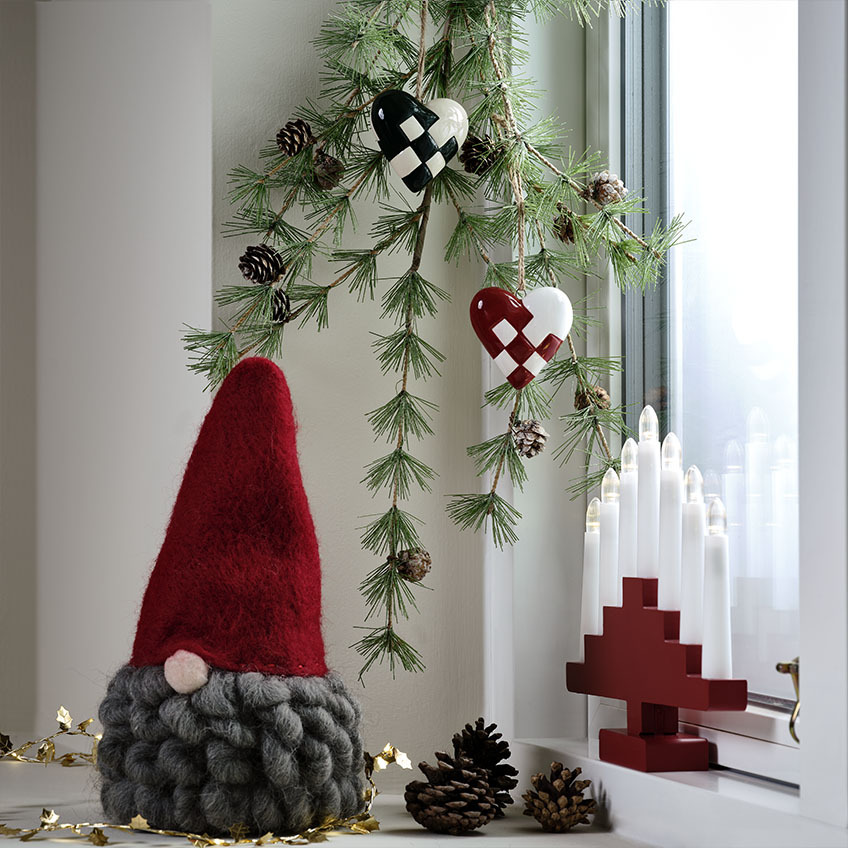 Skandinavski božićni vilenjak sa sedom bradom na ukrašenoj prozorskoj dasci 
