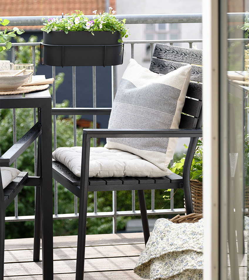 Crna baštenska stolica za slaganje sa jastucima na balkonu