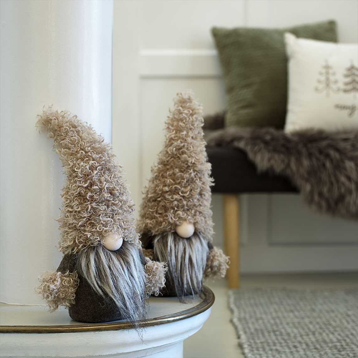 Mali ukrasni novogodišnji vilenjaci u nijansama zelene i smeđe na komodi