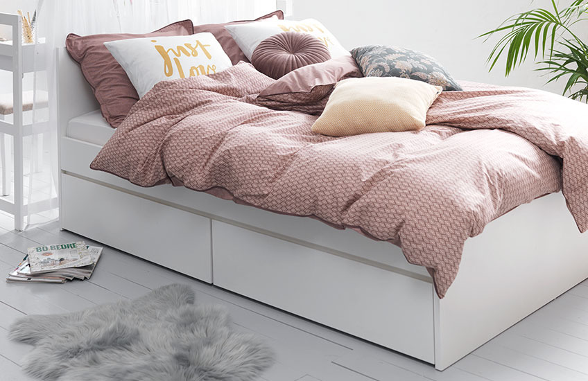Beli ram kreveta sa roze posteljinom u spavaćoj sobi