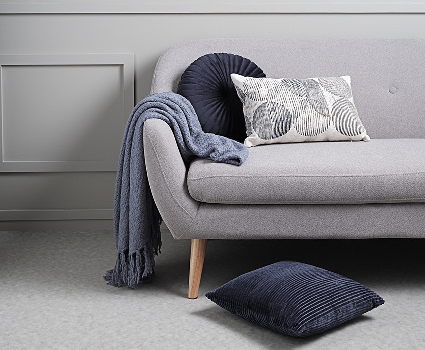 Kauč sive boje sa ćebetom i jastučićima
