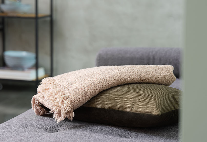 Mekano ćebe i ukrasni jastuk na sofi
