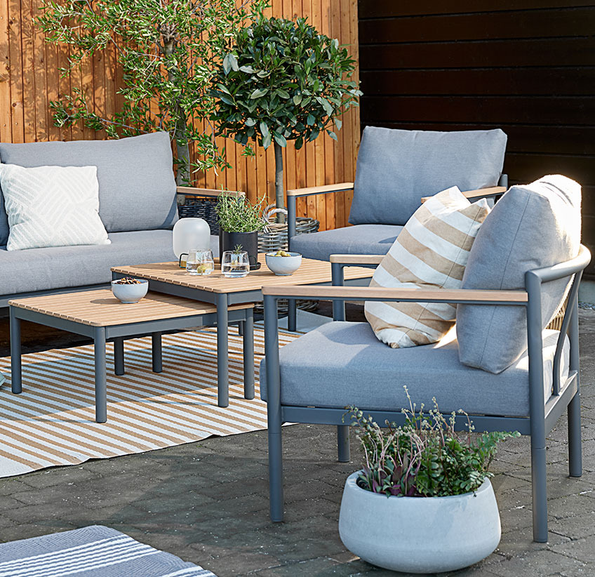 Garden lounge set with comfy cushions on a patio with rugs and planters