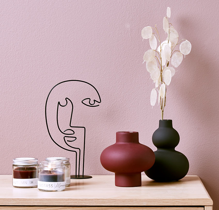 Vaza na stolu sa cvećem i sa skulpturom i tri mirišljave sveće