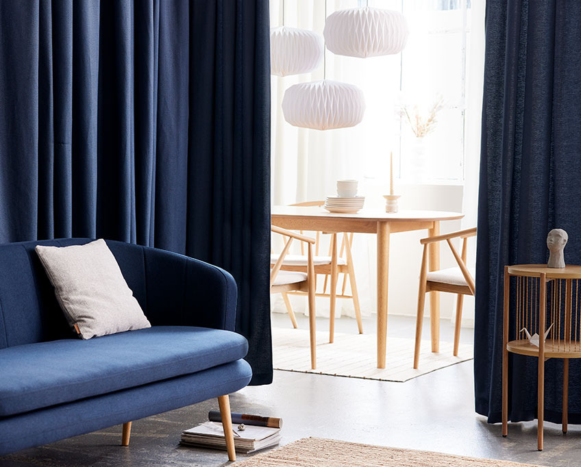 Plave zavese iza sofe razdvajaju dnevnu sobu od trpezarije