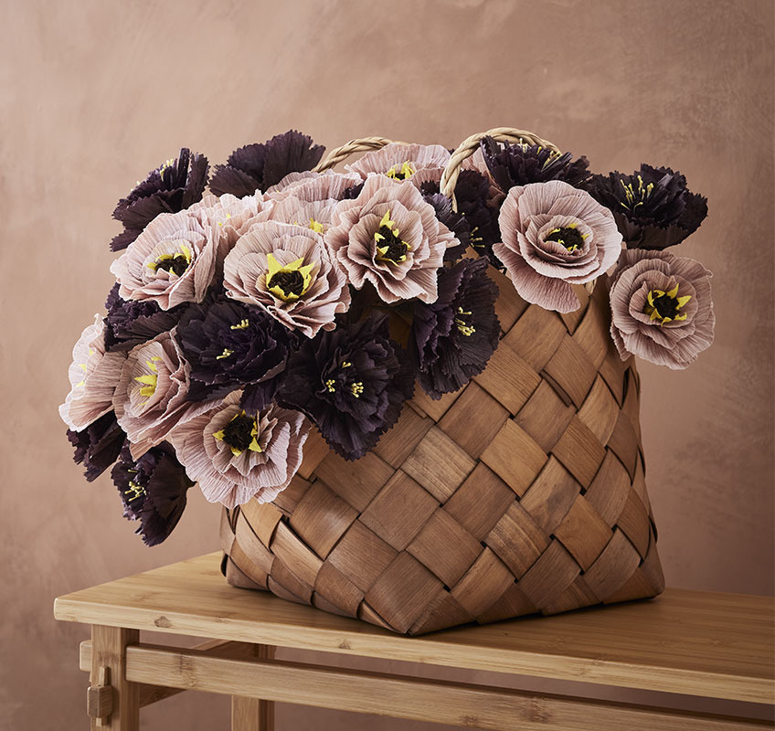 Buket papirnatog cveća stilizovan u korpi od pruća
