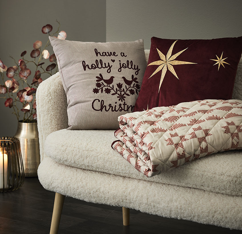 Jastuci i štepano ćebe sa novogodišnjim motivima na belom dvosedu