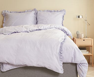Svetloljubičasta posteljina od ispranog pamuka u spavaćoj sobi svetlih zidova